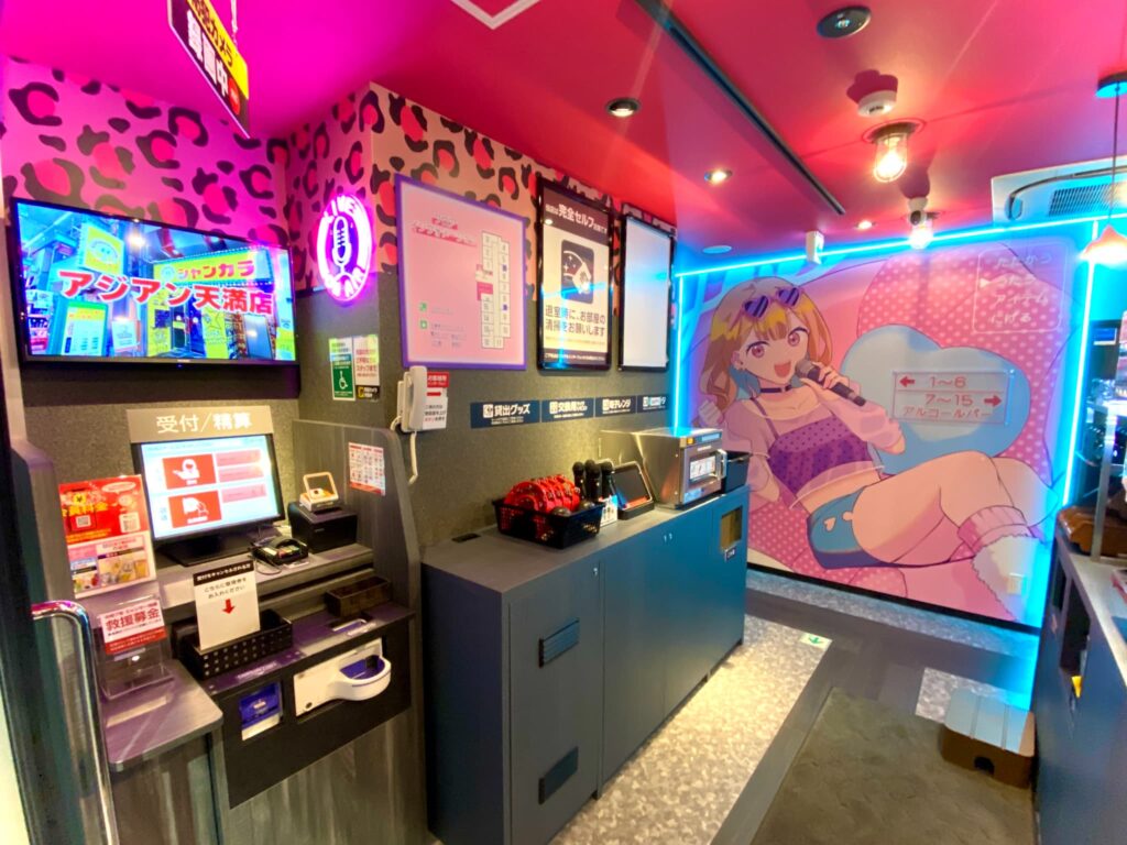 セルフ受付機とアニメ風の壁画が並ぶジャンカラ橘通店の入り口。スマホひとつで入店から精算まで完了できる無人カラオケ受付