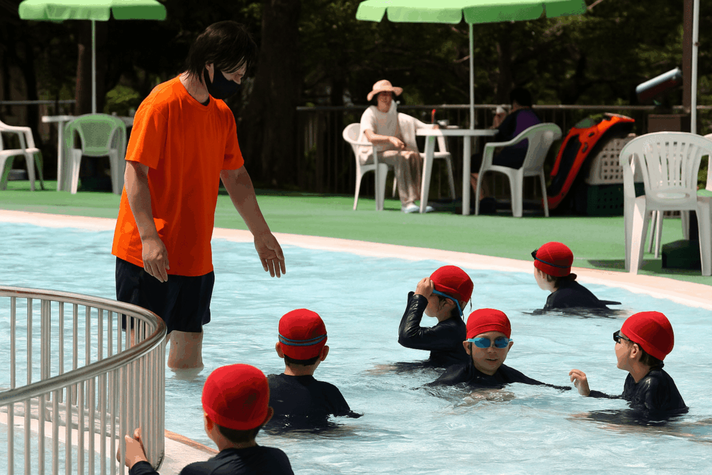 子どもたちが流れるプールでインストラクターの指導を受けながら遊泳している様子